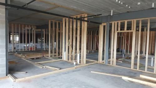 Interior construction site with unfinished wooden stud walls in a concrete-framed building.
