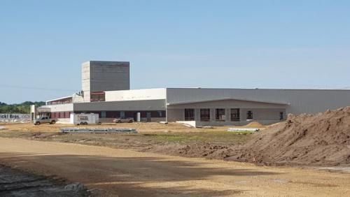 Low-rise industrial building on a barren construction site under a clear sky