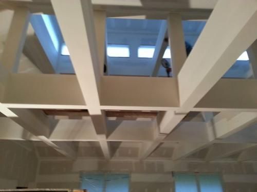 White ceiling beams and skylights in an indoor atrium viewed from below
