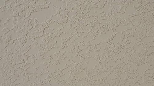 Beige textured stucco wall with subtle shadows and no other objects visible