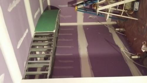 Purple room under construction with ladder, scaffold, and tools on the floor