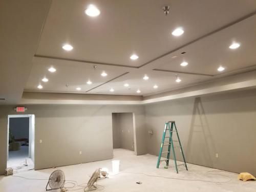 Empty room under construction with recessed lights, a ladder, and a fan on the floor