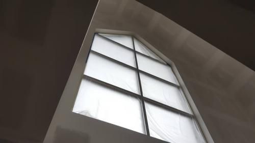 Upward view of a tall window with white panes and dark trim in a building interior