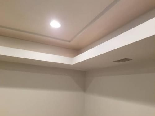 Empty room corner with recessed ceiling lights and a white tray ceiling trim