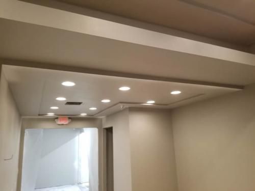 Modern hallway ceiling with recessed lights and a doorway opening to a bright stairwell