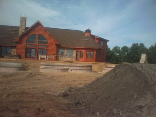 Partially built brick house with large windows and piles of dirt in the foreground.