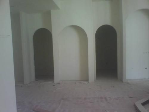 Empty unfinished room with three arched doorways and bare concrete floor