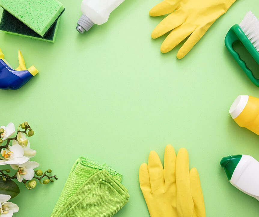 Green cleaning supplies and yellow gloves arranged on a light green background