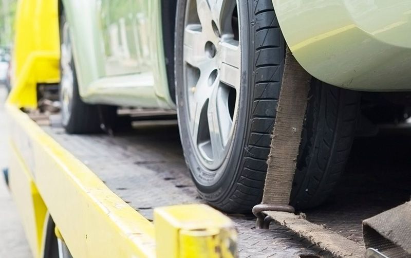 a car is being towed by a yellow tow truck