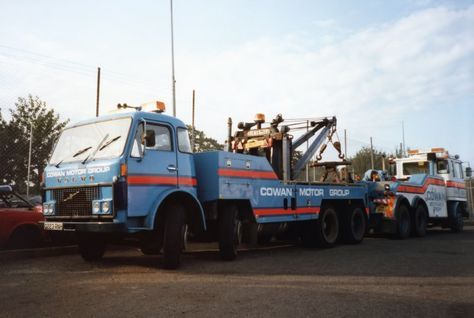 two tow trucks are parked next to each other in a parking lot .