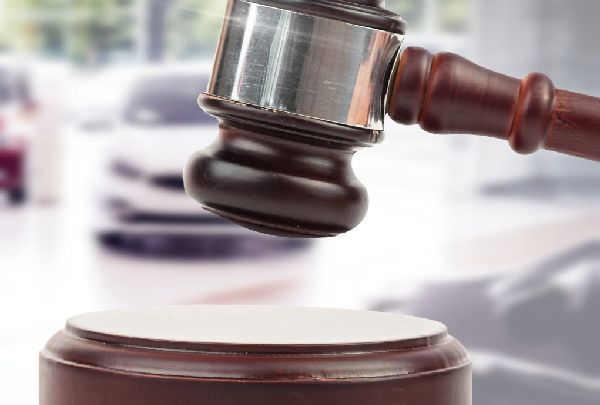 a judge 's gavel is hitting a wooden block in front of a car .