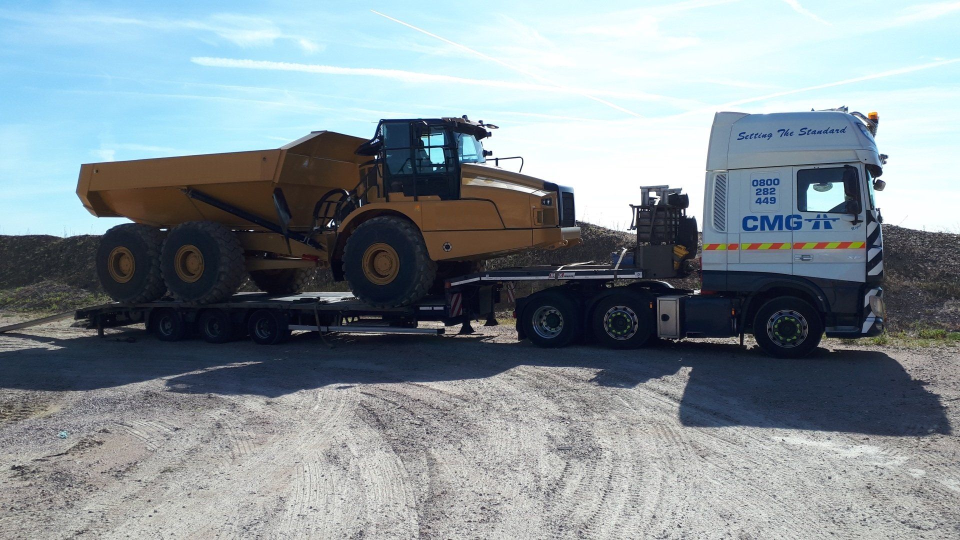 a large dump truck is being transported by a semi truck .