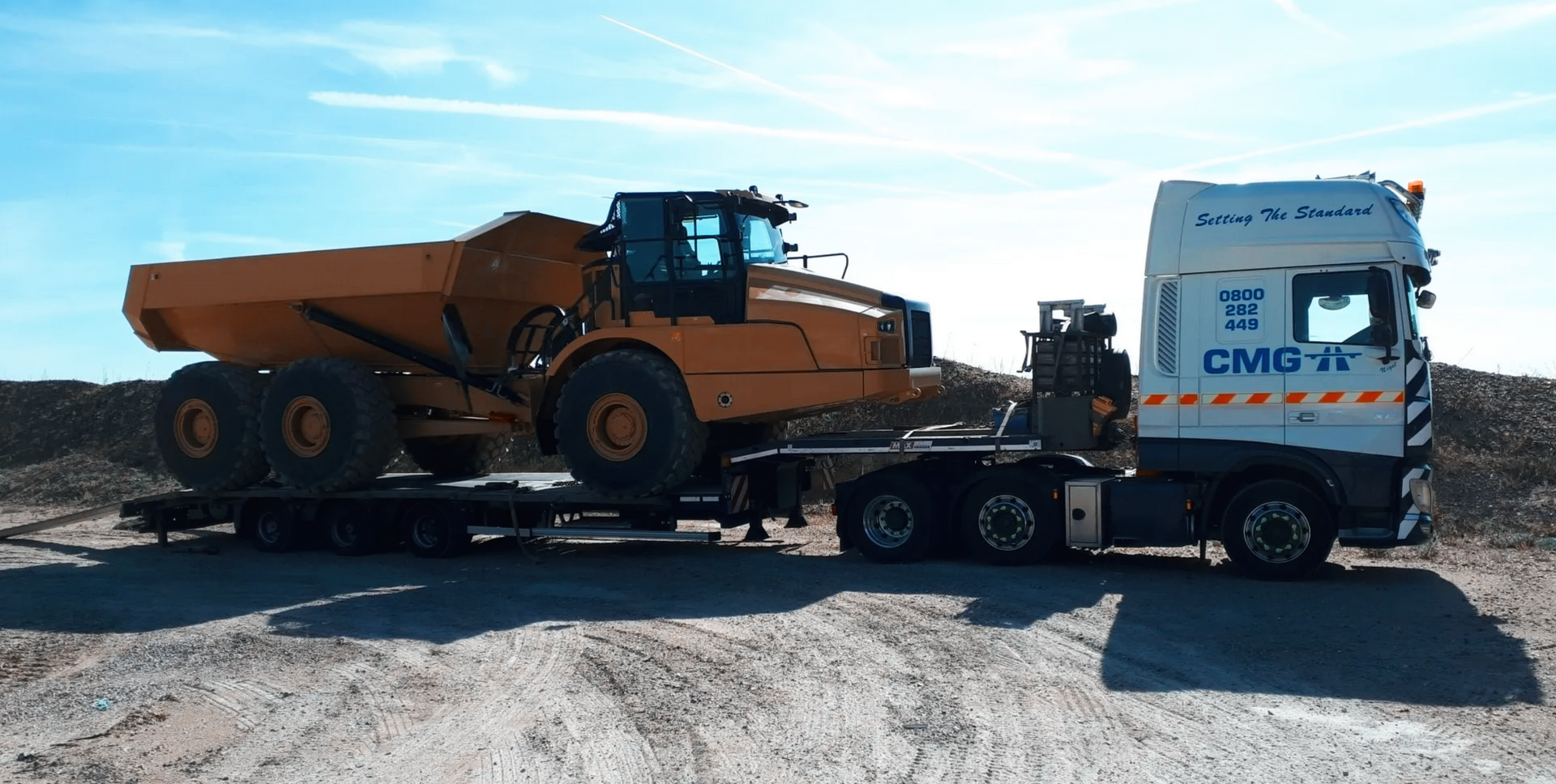 a dump truck is being transported by a cmg truck