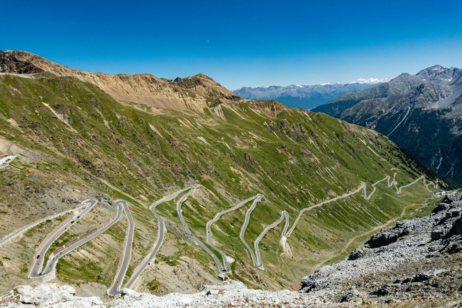 A winding road in the mountains with a blue sky in the background.