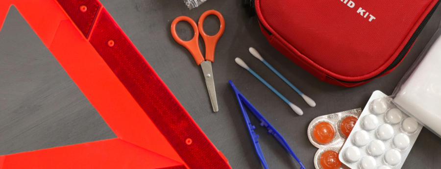 A first aid kit is sitting on a table next to a red triangle.