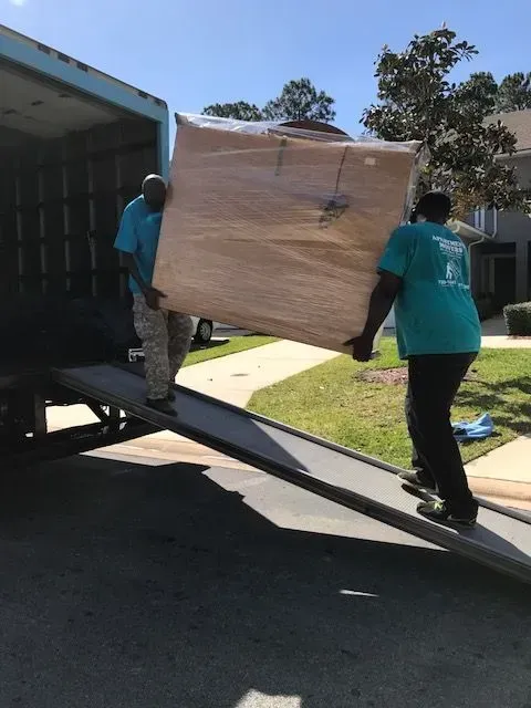 Two people loading cardboard boxes into a van, smiling.