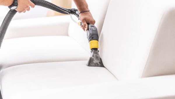 an image of professional sofa cleaning in Hastings taking place. The nozzle of the equipment is grey and yellow.