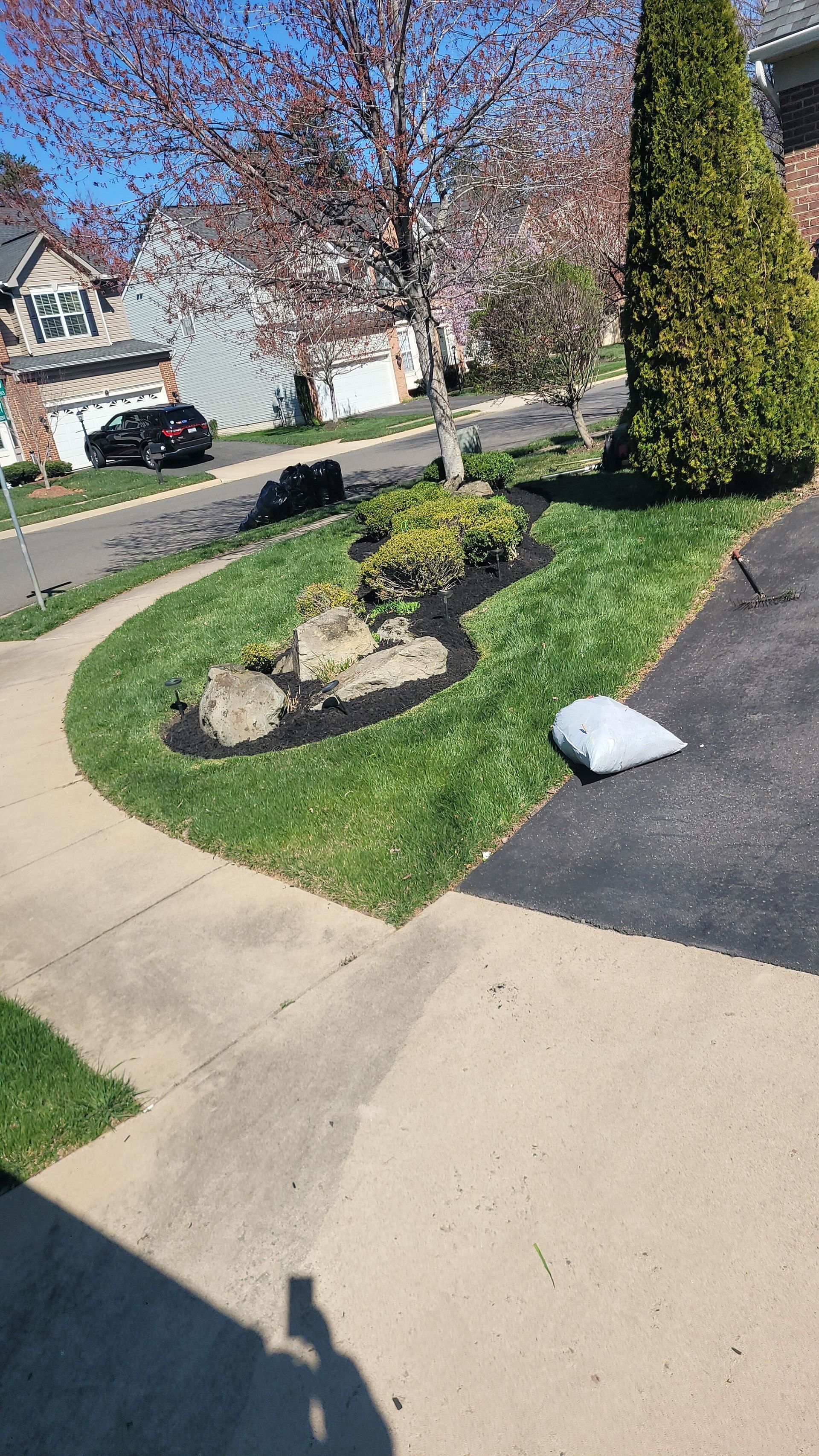 A shadow of a person is cast on a sidewalk in front of a house.