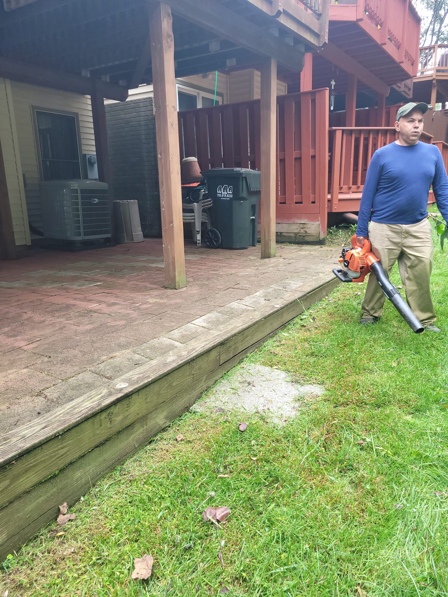 A man is blowing leaves in a yard with a blower.