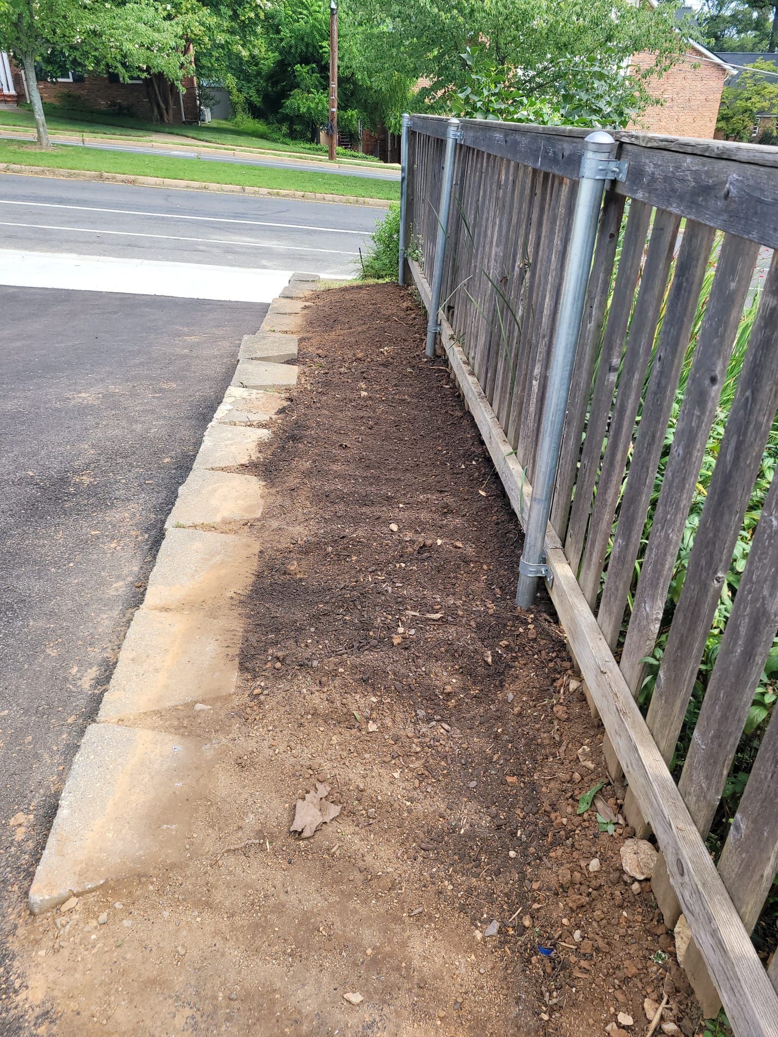A wooden fence along a sidewalk next to a road.