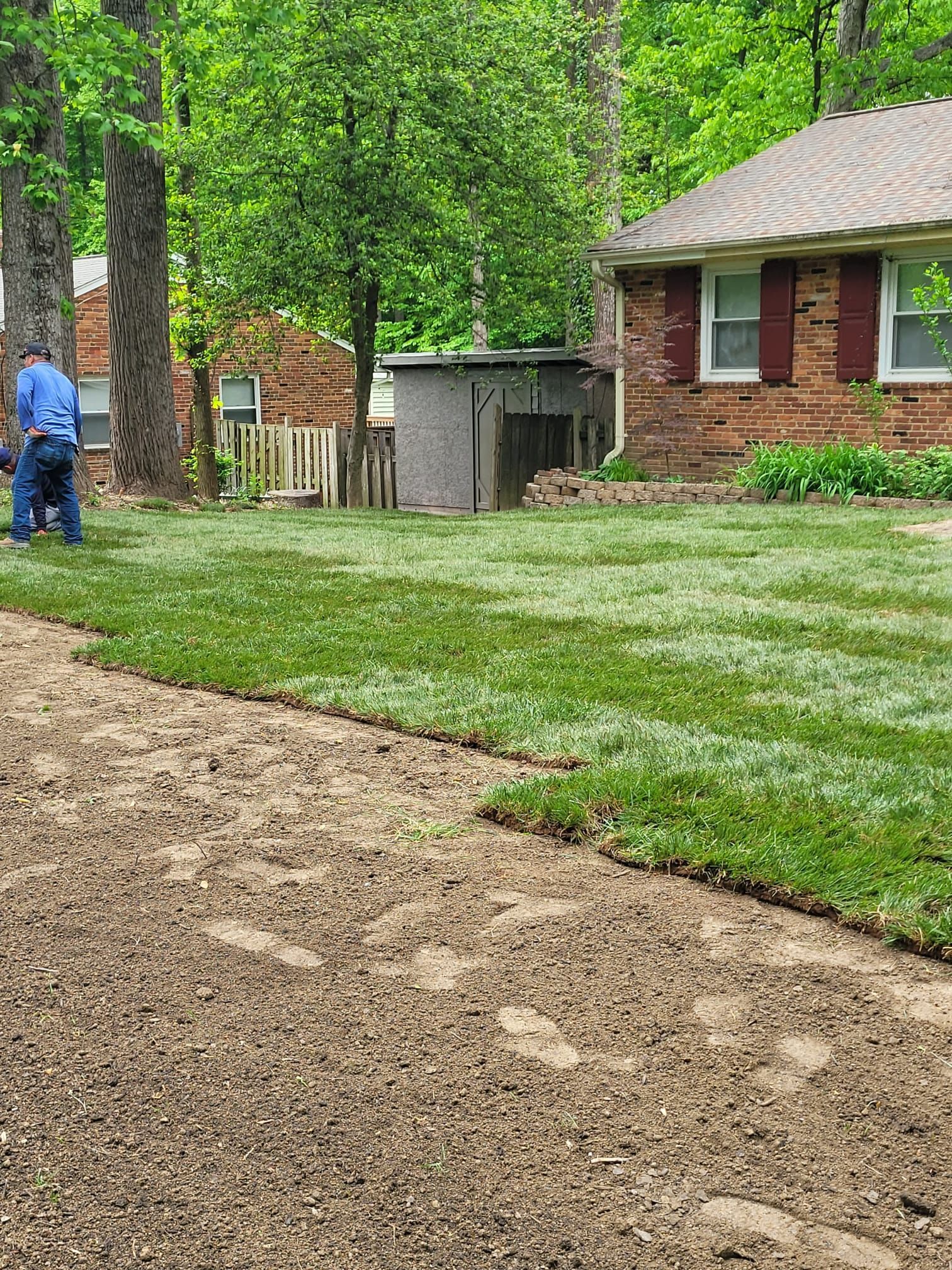 A man is working on a lawn in front of a house.
