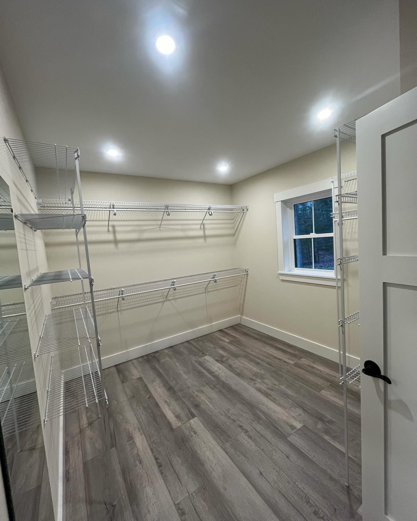 Walk-in closet with wire shelving and gray wood-look flooring. A window provides natural light.