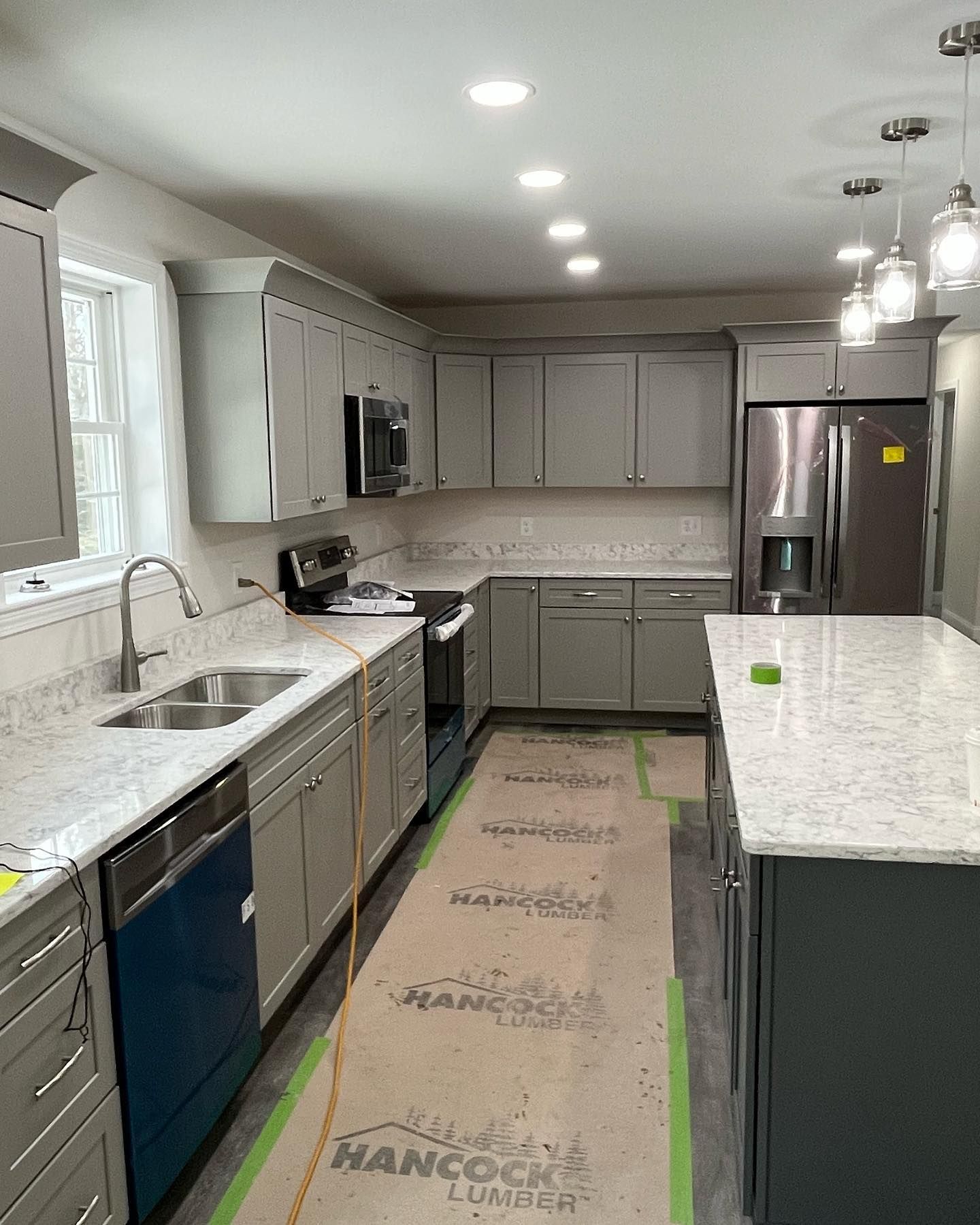 Gray kitchen with cabinets, stainless steel appliances, and island with countertop.