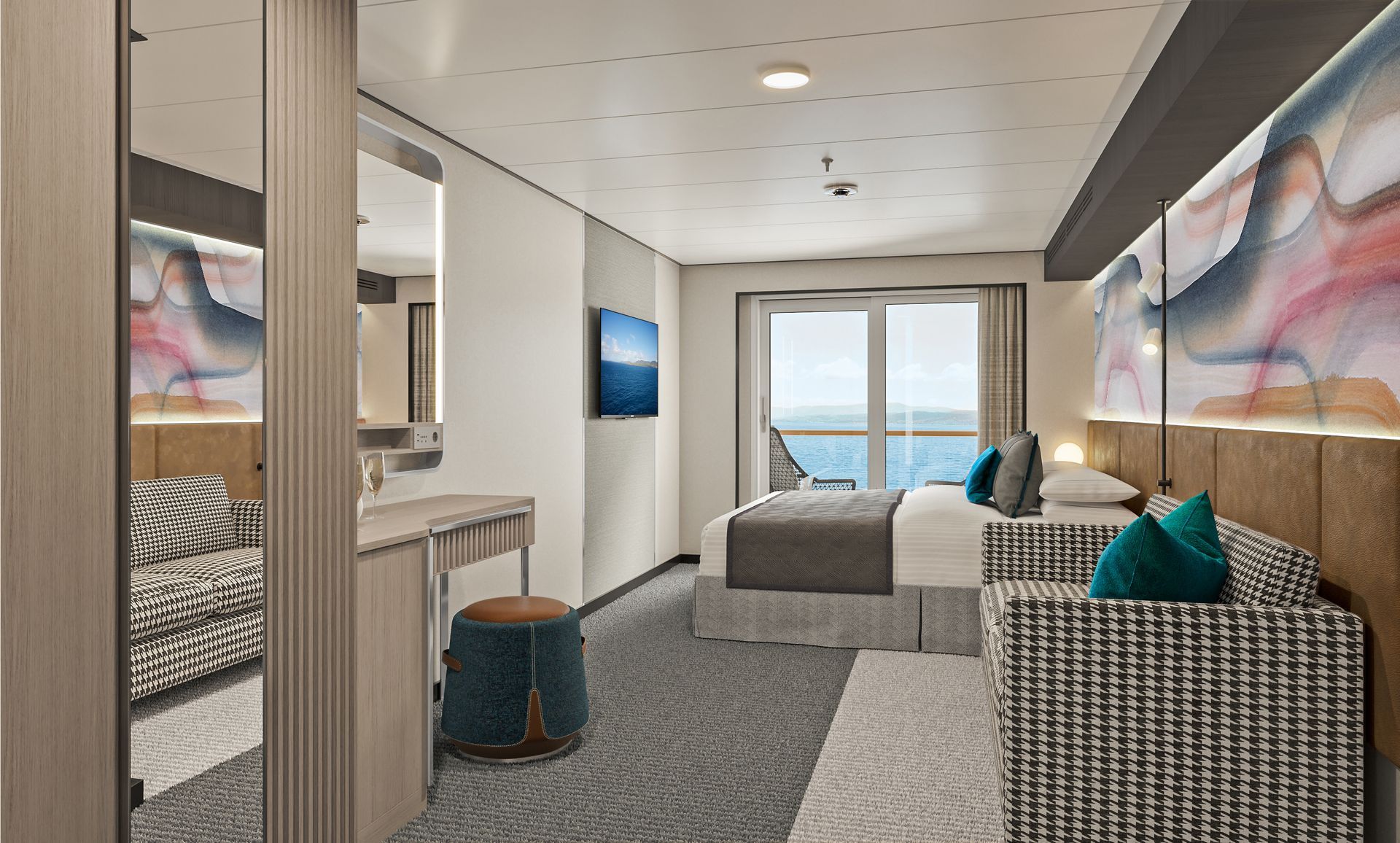 A modern cruise ship cabin with a bed, small sofa, vanity area, and a view of the ocean through a glass balcony door.