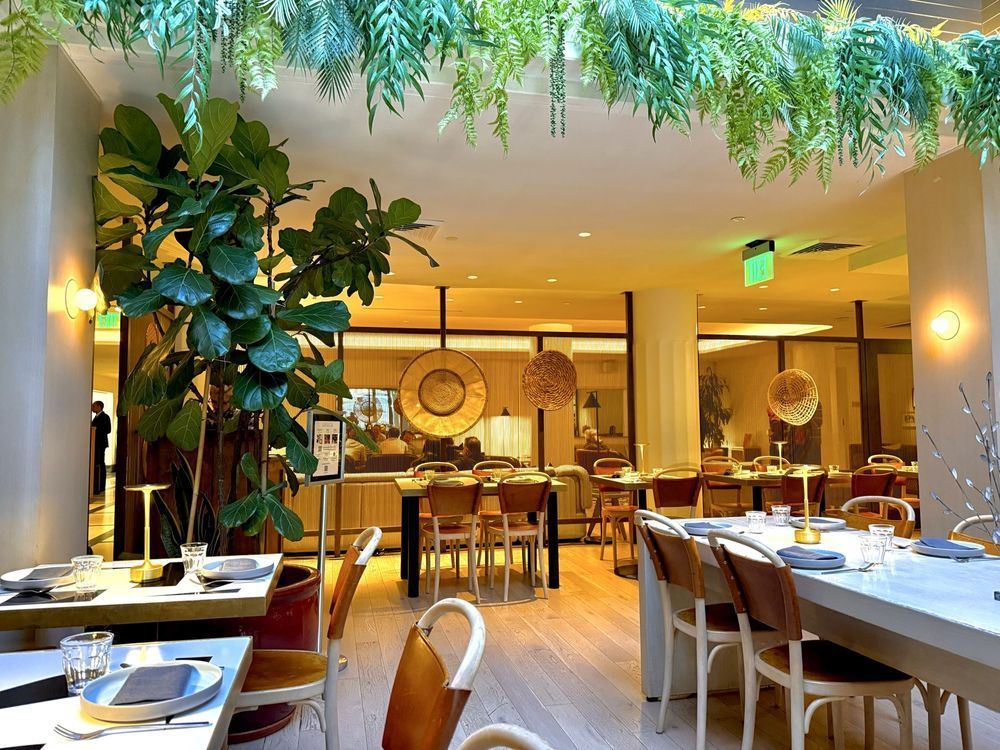 Elegant restaurant interior with lush greenery, warm lighting, and set dining tables