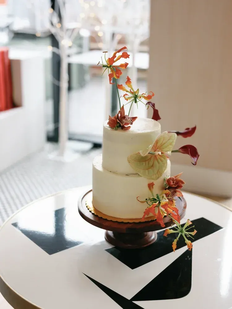 White tiered cake with floral decorations on a black-and-white table in a bright room