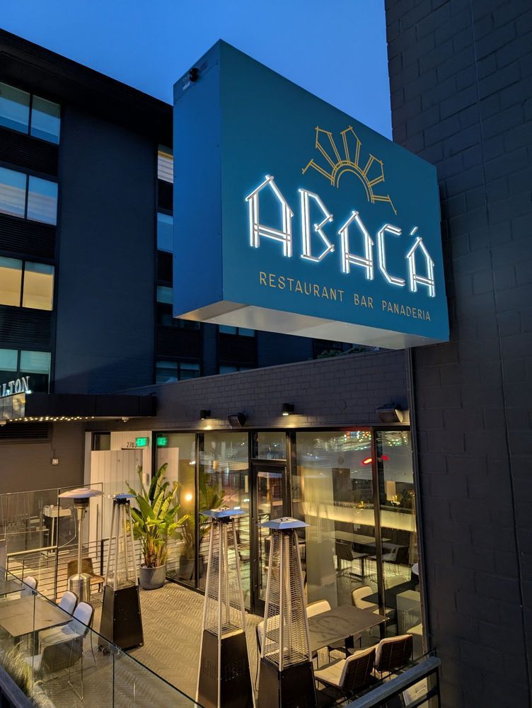 Exterior of ABACA restaurant with blue sign and glass entrance at dusk