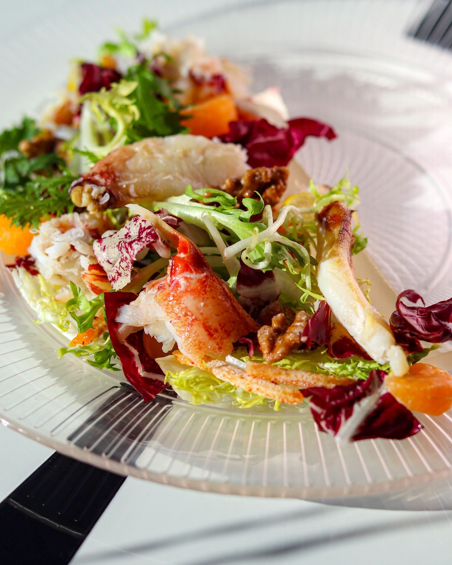 Colorful seafood salad with greens and orange garnish on a white plate