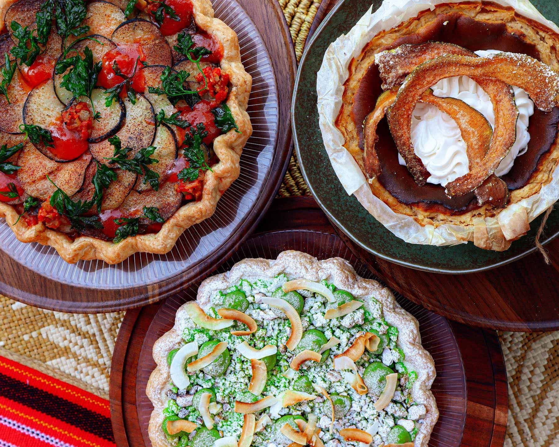 Three decorated fruit tartlets on plates, including strawberry, whipped cream, and kiwi toppings.