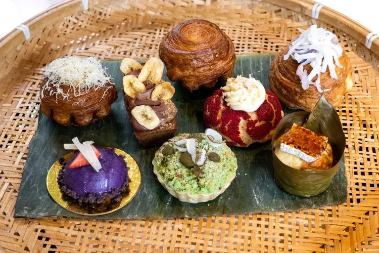 Assorted colorful Japanese sweets arranged on a woven tray with green leaves