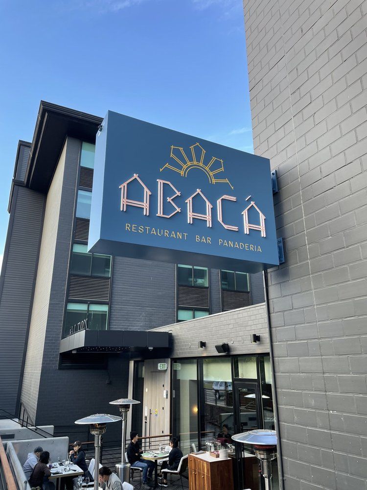 ABACA cafe sign above an outdoor patio at a modern building entrance