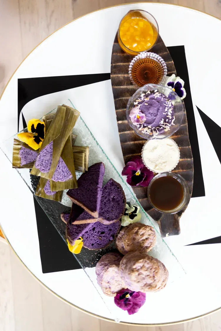 Assorted colorful pastries and cakes arranged on a white plate with black decorative ribbons.