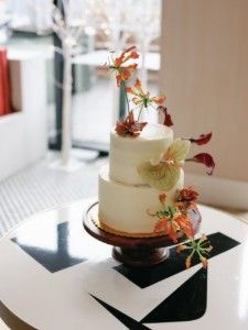 Two-tier white cake with orange floral decorations on a black-and-white table