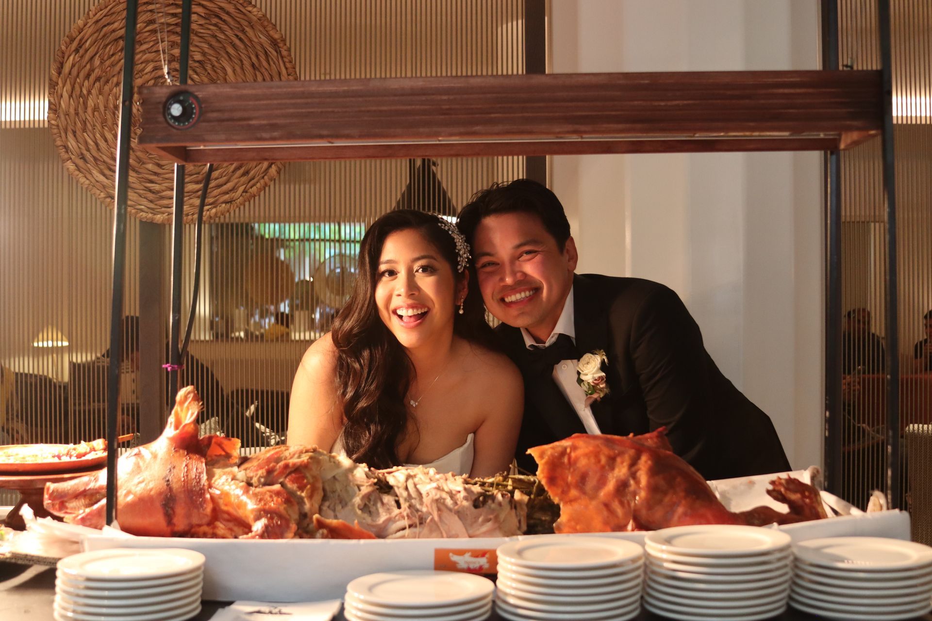 Smiling couple behind a seafood buffet, with stacked plates and a warm indoor reception setting