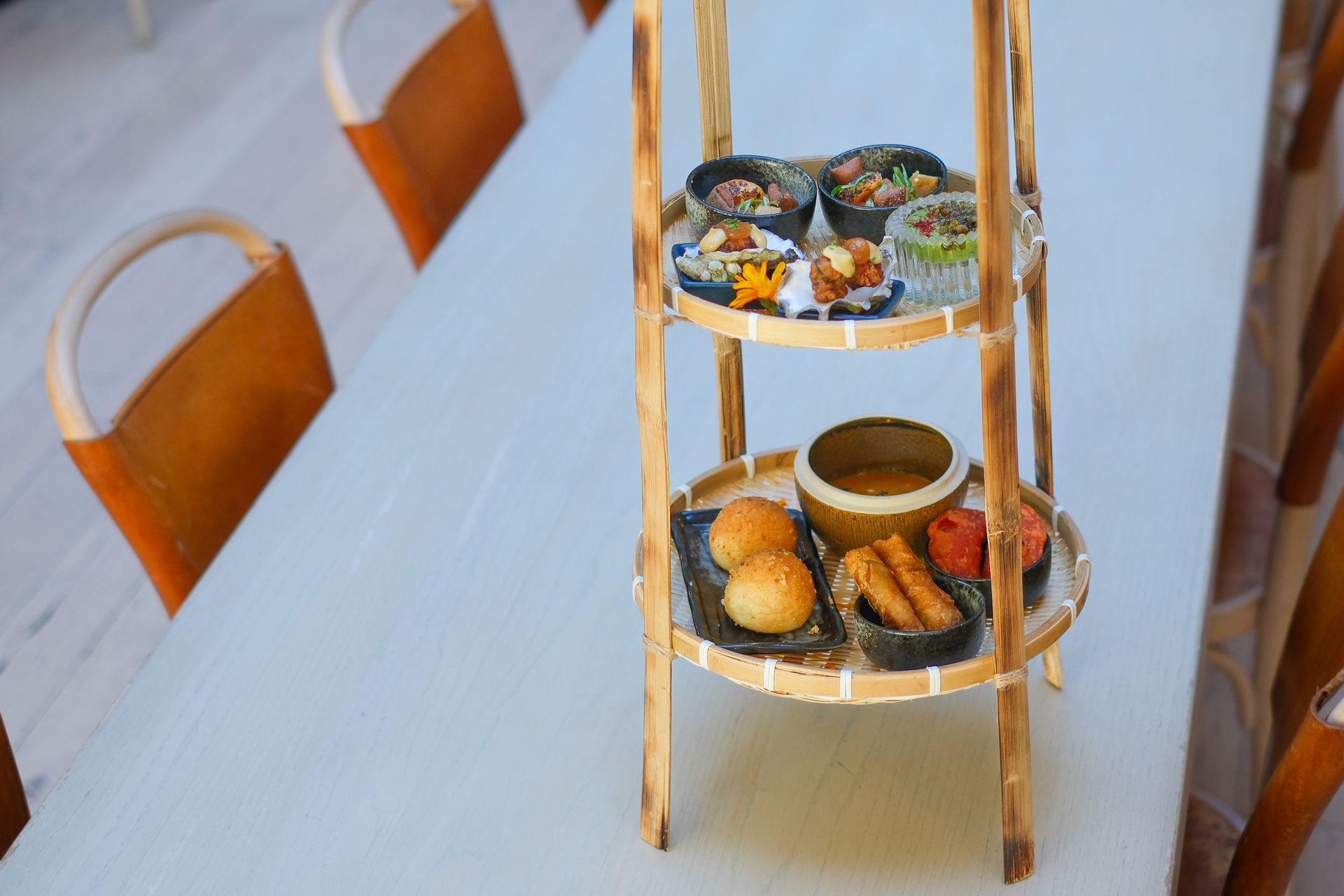 Tiered snack stand with pastries on a table beside orange chairs