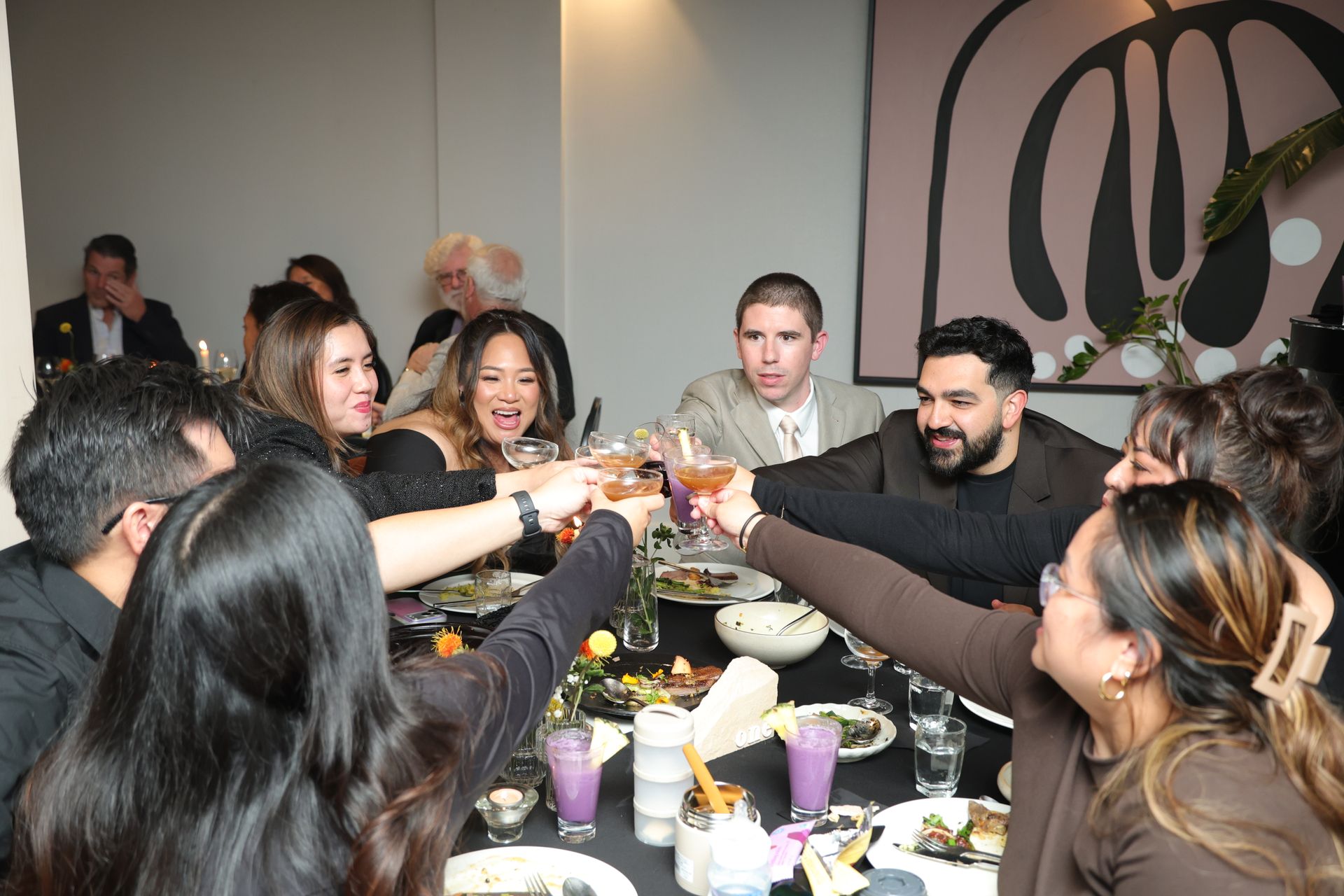 Friends raising glasses over a dinner table in a modern restaurant, smiling and celebrating together