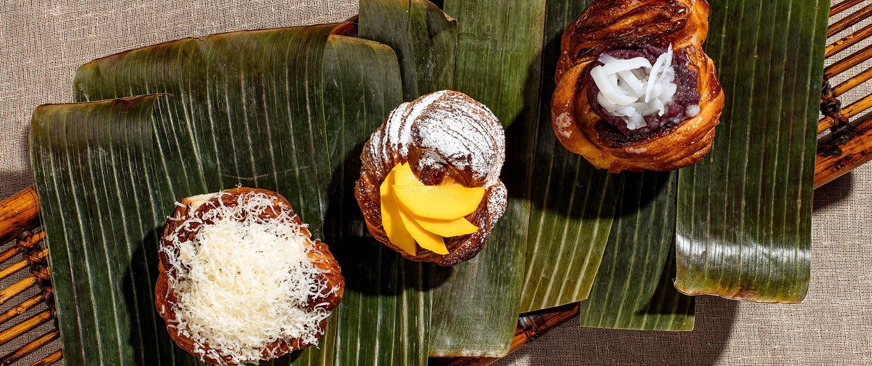 Southeast Asian desserts on banana leaves: round pastries with coconut, purple, and yellow fillings