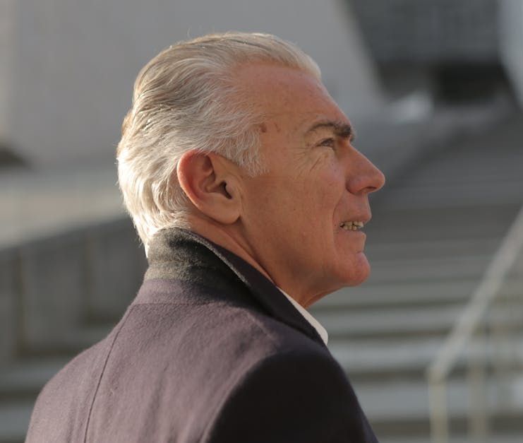 A man in a suit is smiling and looking to the side