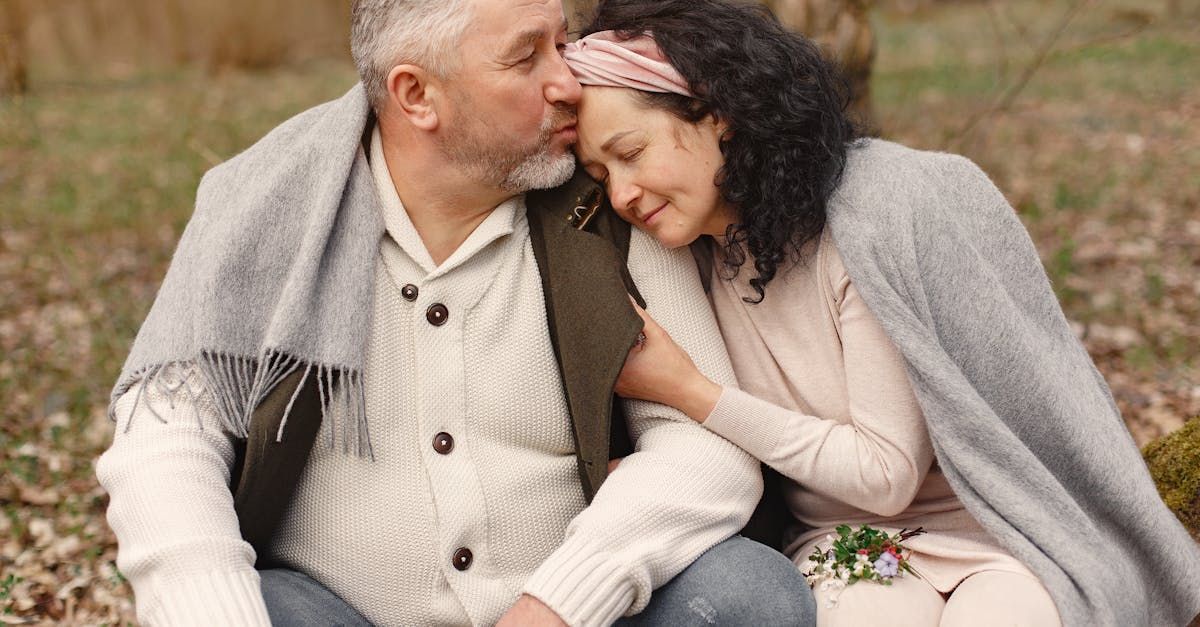 A man and a woman are sitting on the ground in the woods.