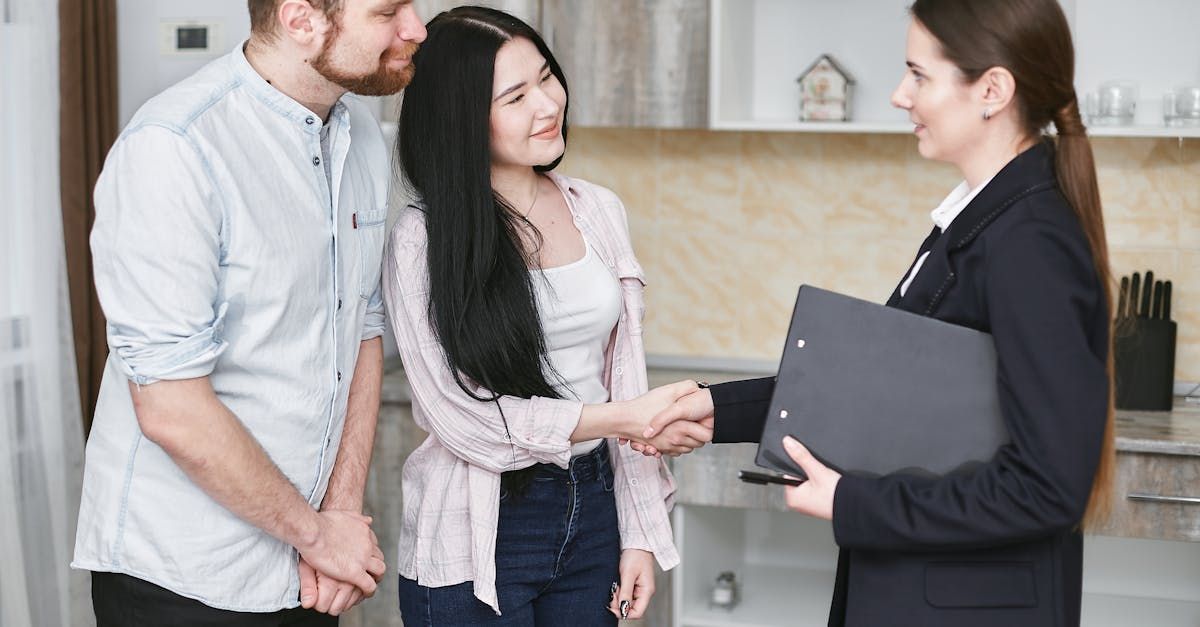 A woman is shaking hands with a man and woman in a kitchen.