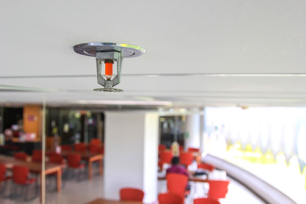 Ceiling Sprinkler in a Restaurant Dining Area With Red Chairs and Tables — Safe Industries Group in Woodrising, NSW