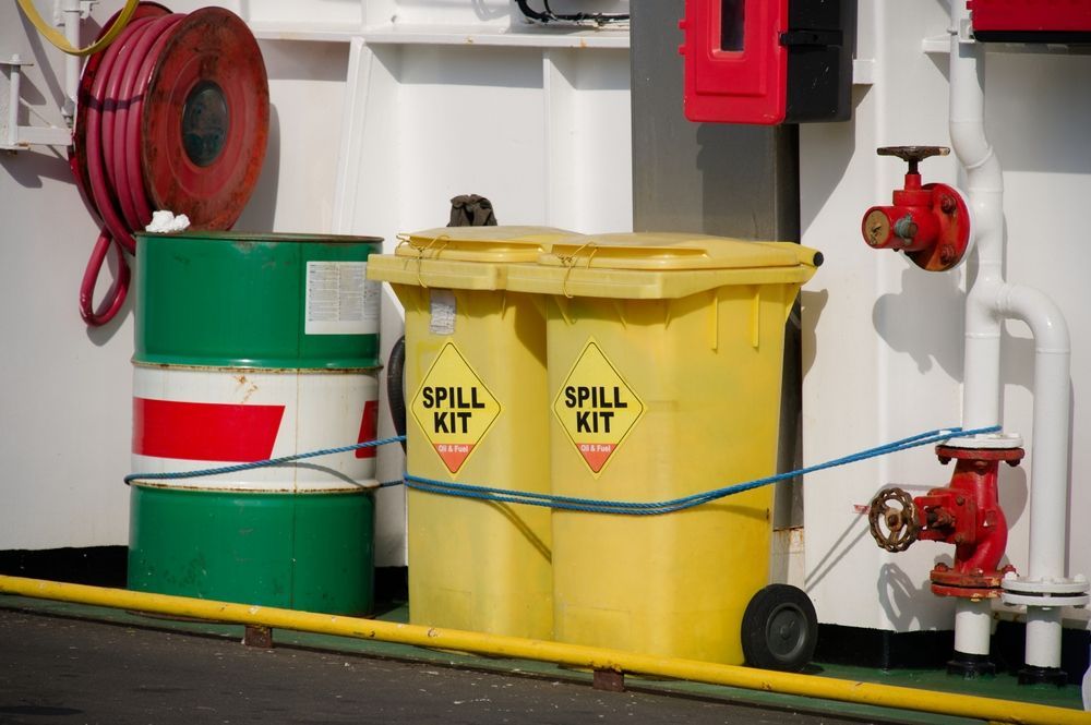 Yellow Chemical Spill Kit Bucket Beside Two Caution Signs — Safe Industries Group in Forster, NSW