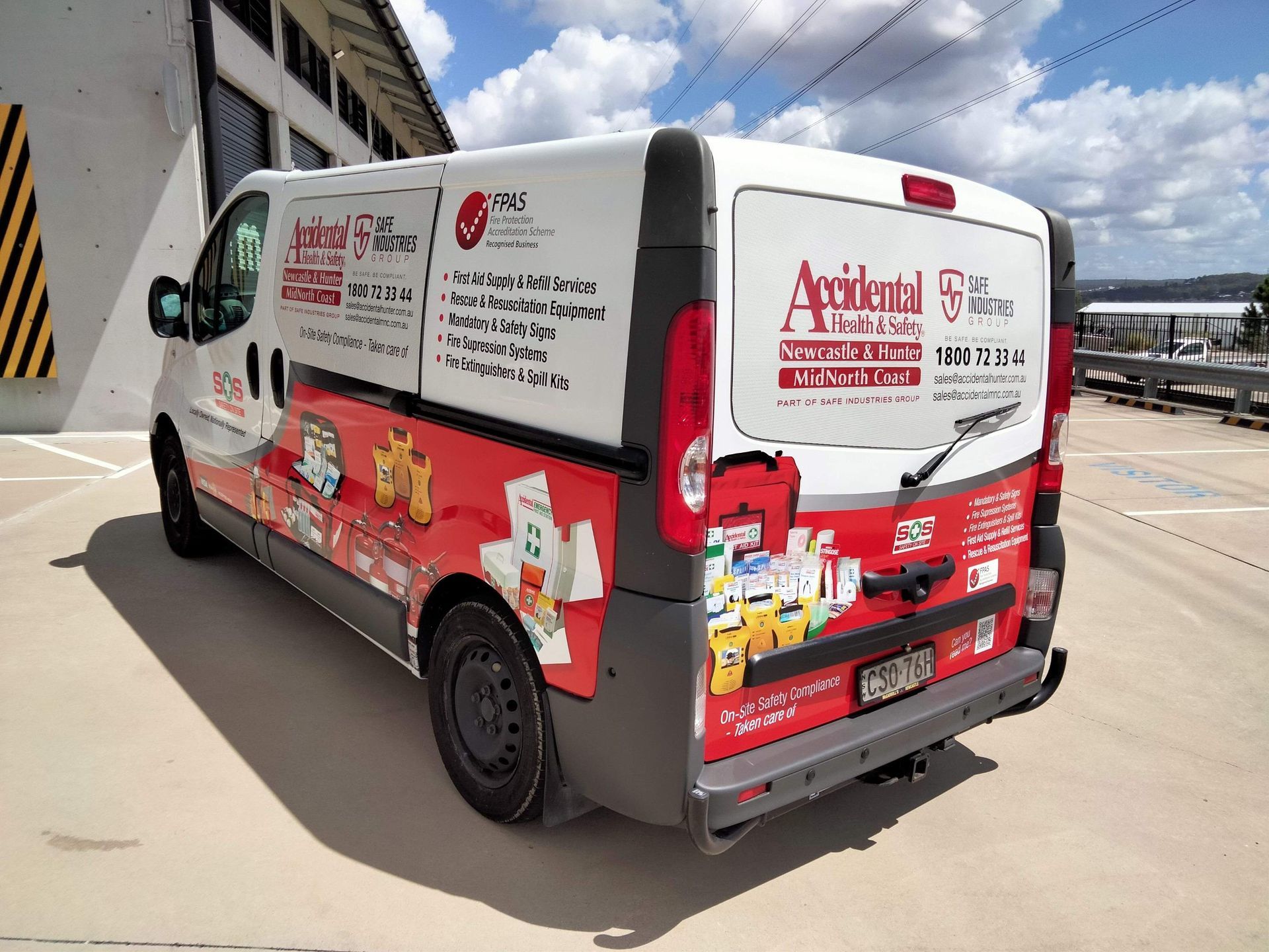 White-and-red branded delivery van parked outdoors beside a building and waterfront — Safe Industries Group in Woodrising, NSW