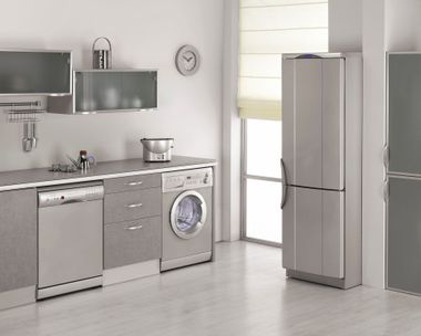 Modern kitchen with stainless steel appliances, gray cabinets, and a refrigerator by a bright window