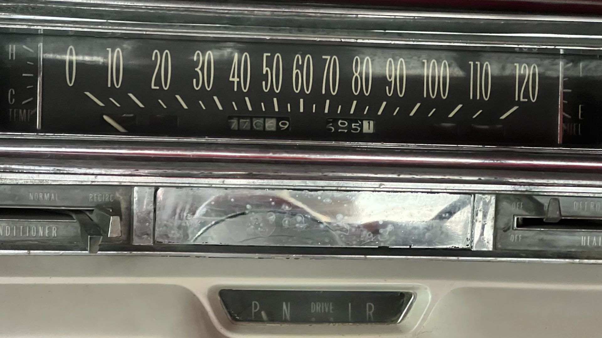 תקריב של רדיו בלוח המחוונים של מכונית וינטג' עם חוגת כוונון אופקית וגימור כרום.