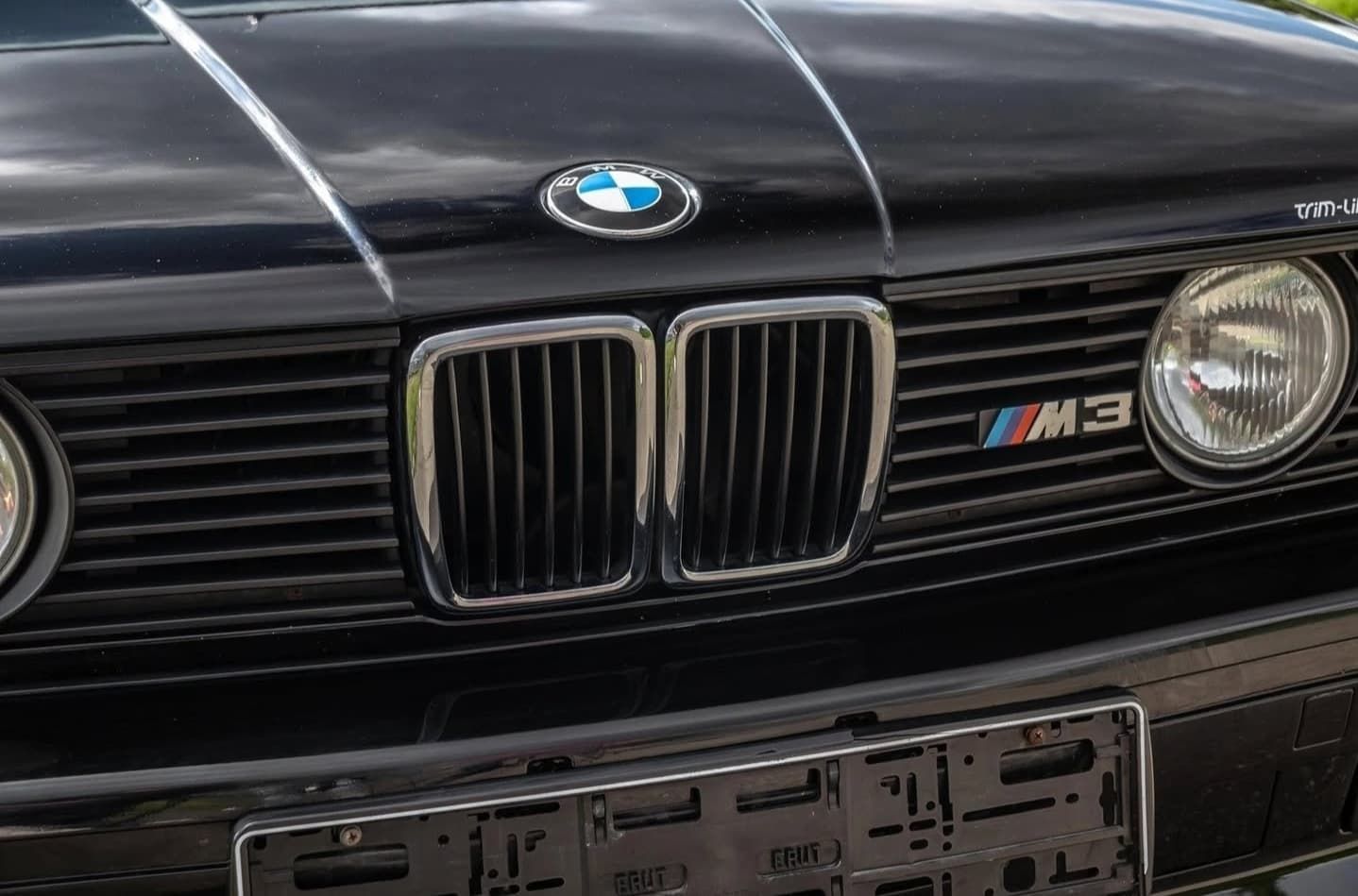 חזית של BMW M3 שחורה עם גריל, פנסים ותג מכסה המנוע גלויים